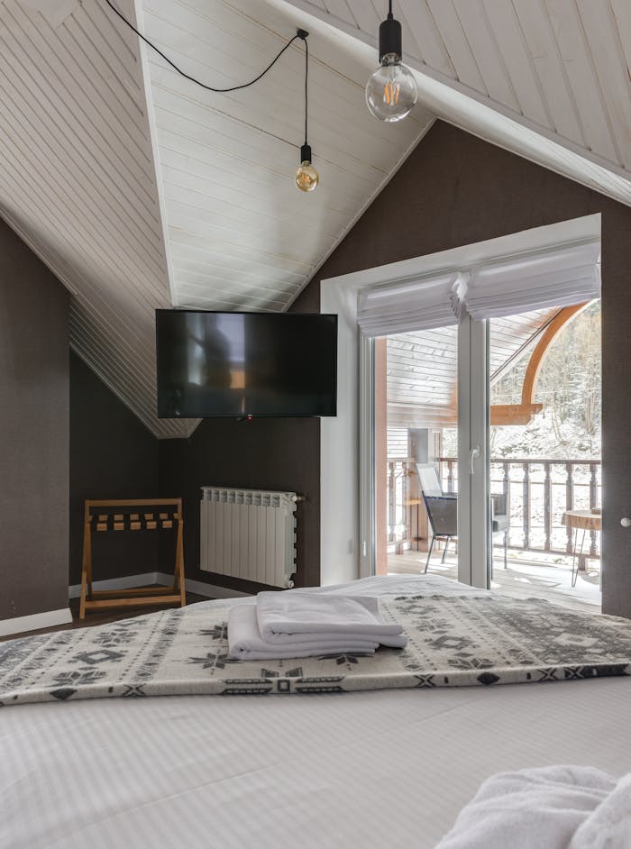 Modern attic bedroom with TV, balcony, and contemporary design elements.